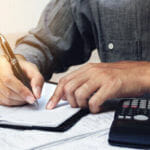 Man budgeting with pen, paper, and calculator
