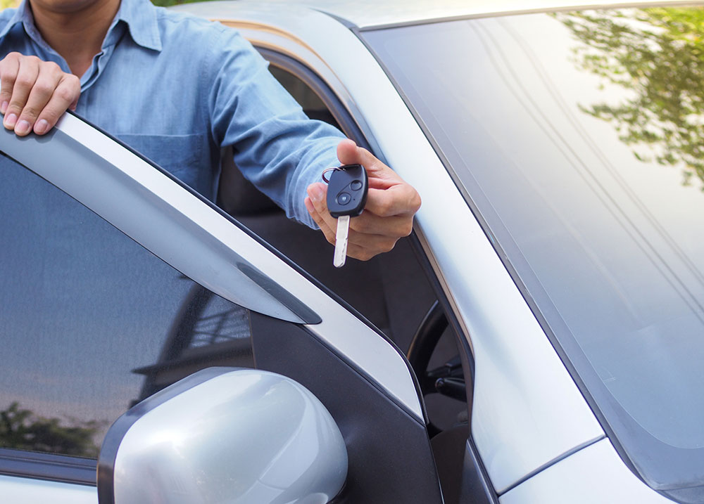 Car owner handing keys to a loan guarantor, illustrating how a cosigner can still be responsible for a loan if the borrower files bankruptcy.