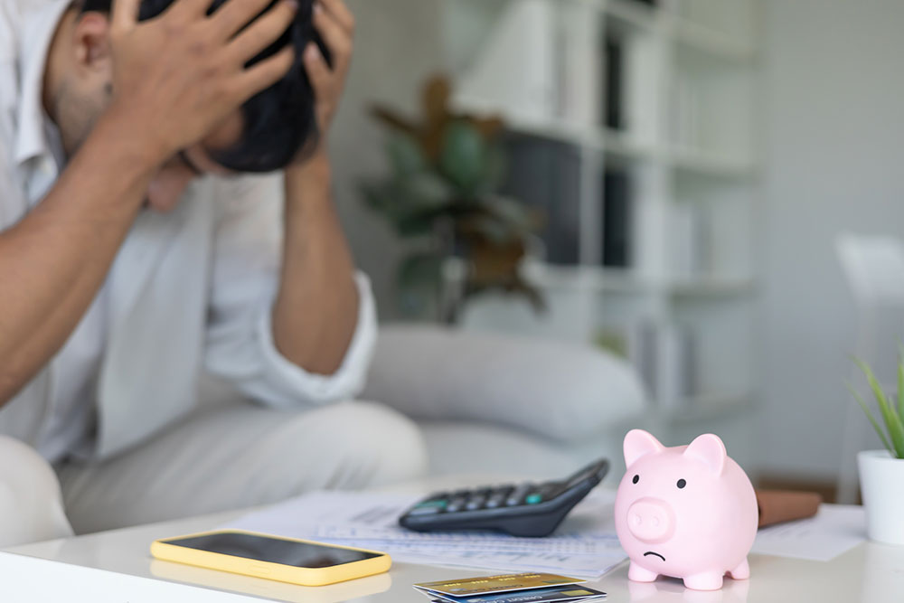 Stressed man reviewing large bills and credit card statements before bankruptcy